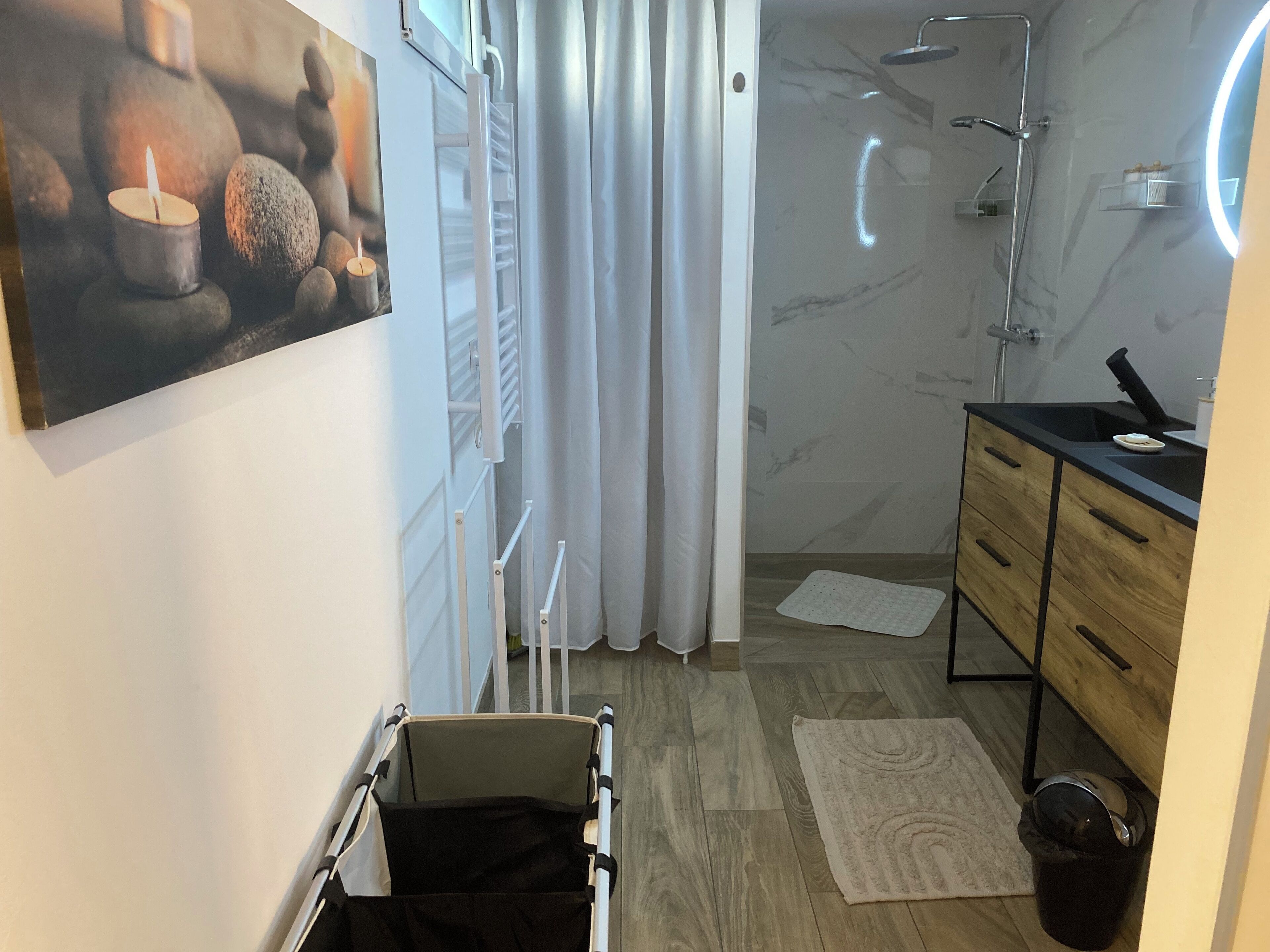 A bathroom with a shower, a sink, a mirror, and a towel rack.