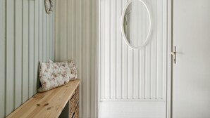 Una habitación con un banco de madera, un espejo y una puerta con paneles verticales.