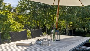 Un espacio comedor al aire libre con una mesa, sillas y una sombrilla.