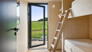 A modern room with a bunk bed, a wooden ladder, and a large sliding glass door leading to a grassy outdoor area. - "Aatos" - 250m from the sea by Interhome (Knebel)