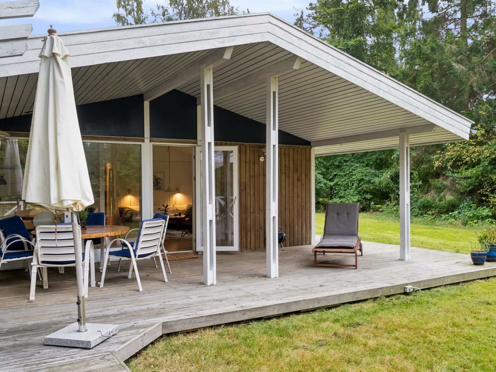 Une terrasse extérieure moderne, dotée d’une plateforme en bois, d’une table avec des chaises et d’un fauteuil de relaxation.