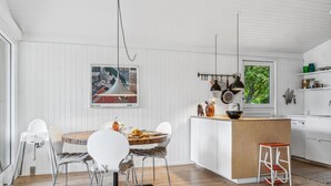 A modern kitchen with white cabinetry, a wooden island, and pendant lighting.
