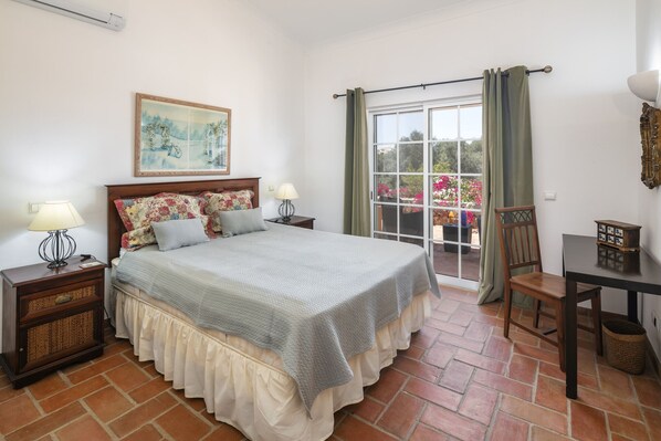 Une chambre à coucher avec un lit, des tables de chevet, une table et une vue par la fenêtre.