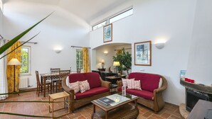 Una sala de estar con dos sofás rojos, una mesa de centro, una chimenea y un comedor.