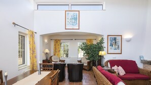 Amplia sala de estar con techo alto, mesa de comedor con sillas, sofá y chimenea.
