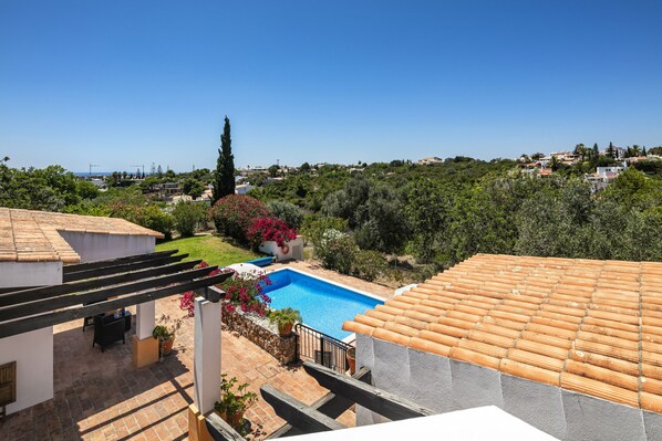 A rooftop pool with a clear view of the surrounding landscape, including a garden and distant buildings.