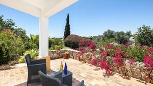 Un patio al aire libre con mobiliario de mimbre y una pared de piedra.