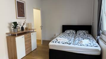 Un dormitorio con cama, mesita de noche, cómoda y un cuadro en la pared.
