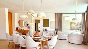 A modern dining area with a wooden table, white chairs, and pendant lighting. - Palais Harmonia (Marrakech)