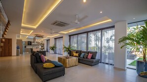 A spacious living area with two sofas, a coffee table, and a ceiling fan. - Villa Manglar Luxury Oceanfront (Las Terrenas)
