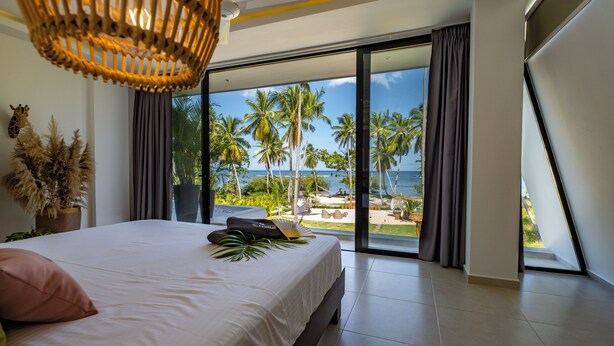A bedroom with a large bed, a view of the beach, and a balcony. - Villa Manglar Luxury Oceanfront (Las Terrenas)