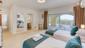 Une chambre d’hôtel avec deux lits, un coin salon, une salle de bain et un balcon avec vue.