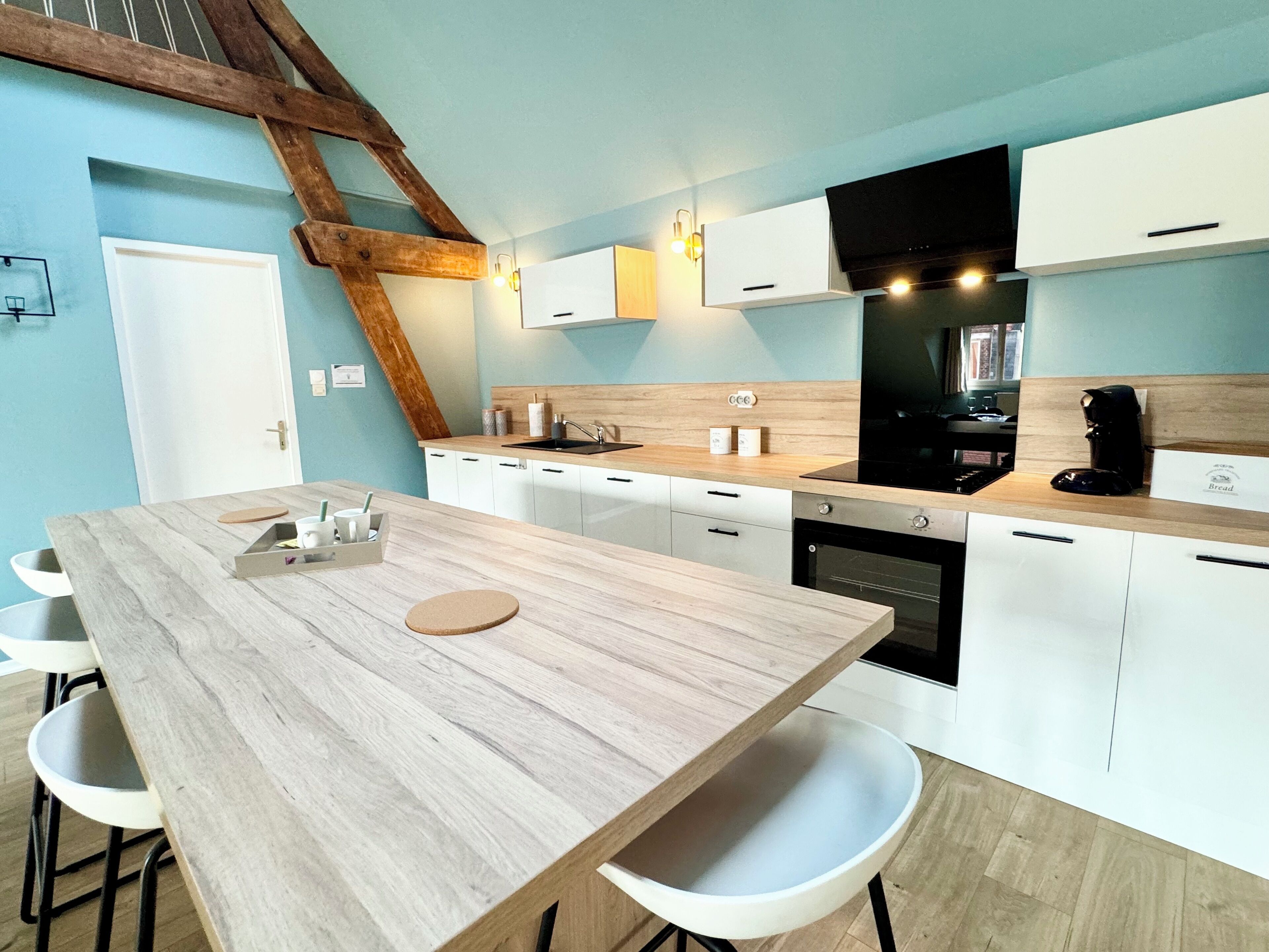 A modern kitchen with a wooden table, white cabinets, and a built-in oven.