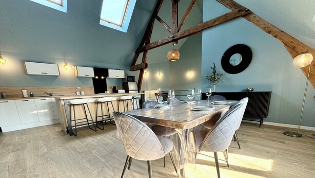 Una cocina moderna con una isla grande, taburetes de bar y una mesa de comedor para cuatro personas.