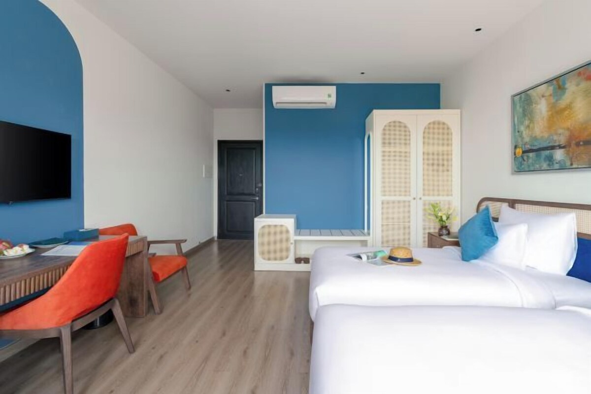 Une chambre d’hôtel avec un lit, un bureau et une chaise, un téléviseur fixé au mur et une fenêtre.