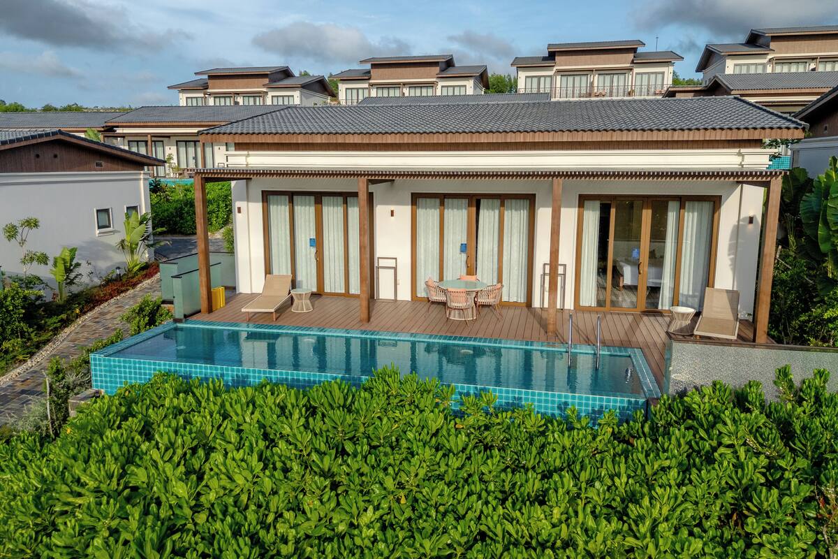 A modern villa with a swimming pool, large windows, and a covered patio area.