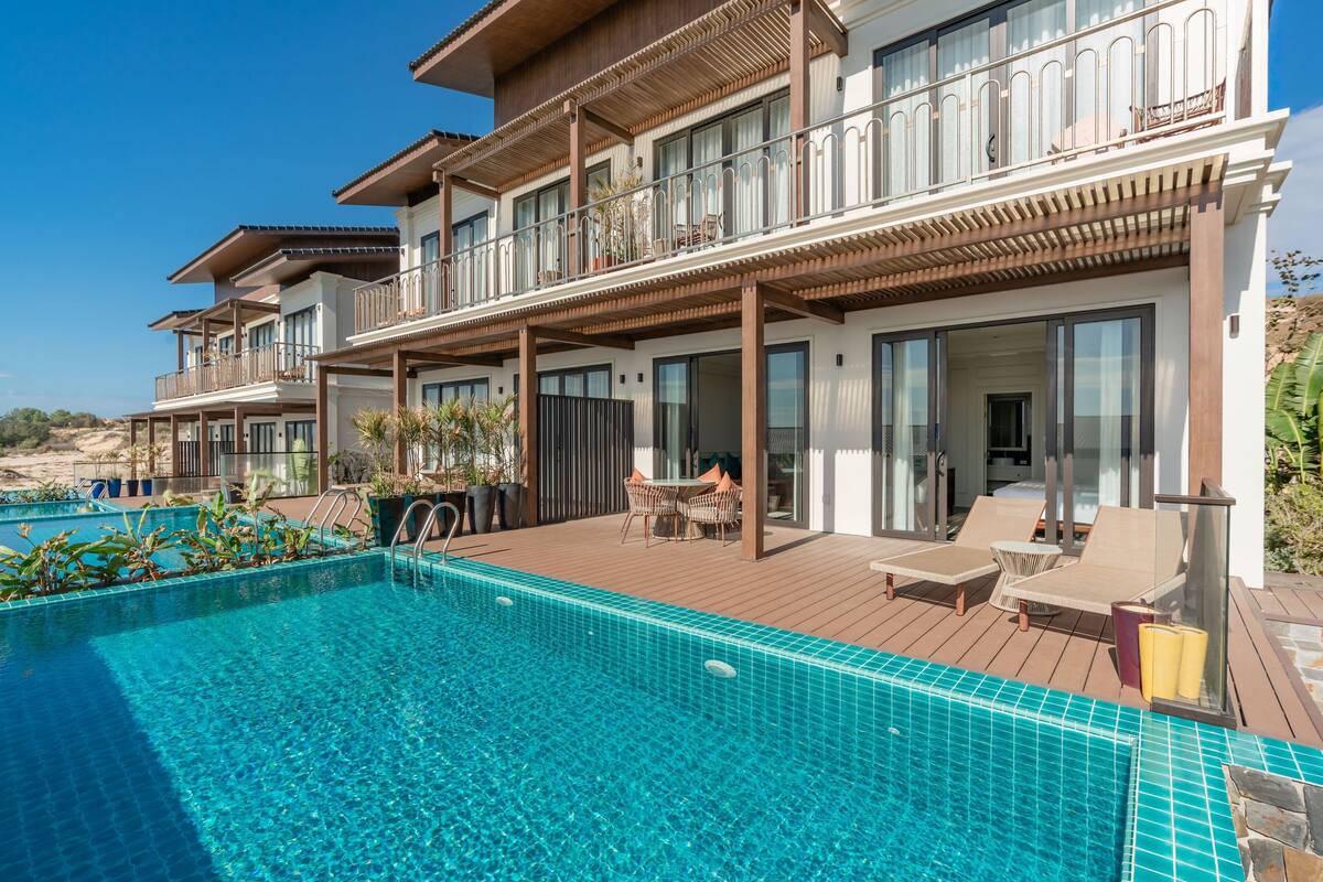 A modern hotel with a pool, outdoor seating, and a view of the beach.