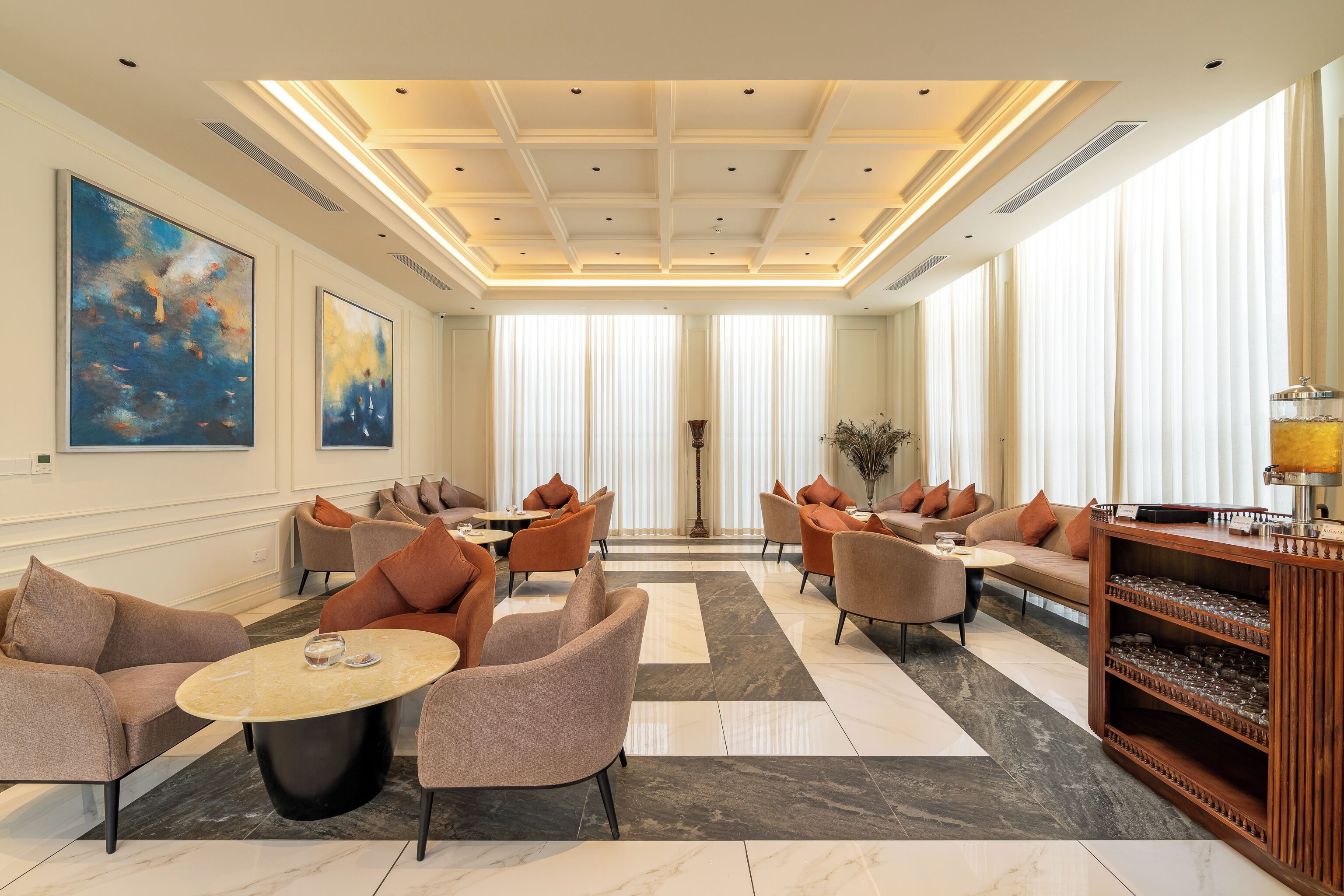 A spacious lobby with modern furniture, large windows, and artwork on the walls.