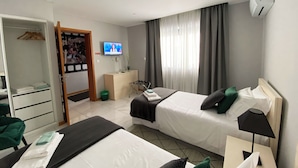 Habitación de hotel con dos camas, televisión, armario y un pequeño escritorio.