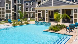 A residential building with a swimming pool, outdoor seating, and a barbecue area.