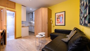 Una sala de estar moderna con un sofá de cuero negro, una mesita blanca y un cuadro enmarcado en la pared.