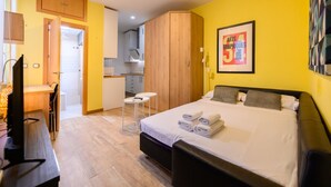 Una habitación de hotel con cama, escritorio, silla, mesita y armario.