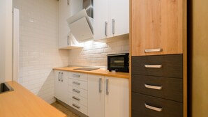 Una cocina con armarios blancos, un microondas y una encimera de madera.
