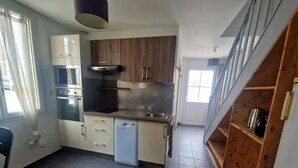 A compact kitchen with a built-in oven, microwave, and dishwasher. It features wooden cabinets and a small countertop.