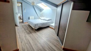 A bedroom with a sloped ceiling, a skylight, a bed, and a radiator.