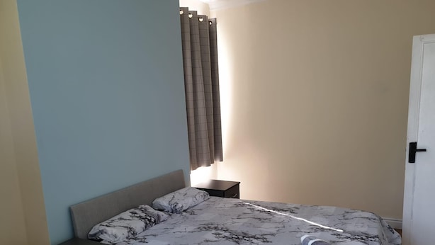Un dormitorio con una cama, una mesita de noche, un aparador y una puerta.