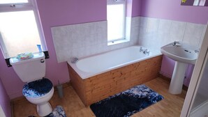 Un baño con bañera de madera, lavabo blanco y un inodoro.