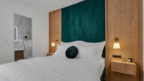 Une chambre d’hôtel moderne avec un grand lit, une tête de lit en bois et des lampes de chevet.