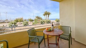 A balcony with two green chairs, a wooden table, and a bottle of champagne. - Apartamento Miramar (Denia)