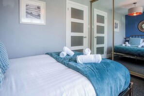 A bedroom with a large bed, a mirror, and a framed picture on the wall.