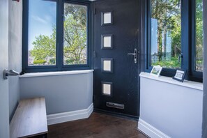 A dark blue door with four square windows, a white baseboard, and a small bench.