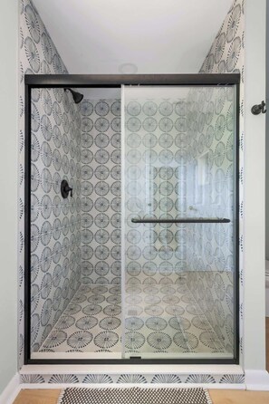 A shower enclosure with a patterned glass door and a towel rack inside.