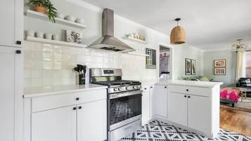 Een moderne keuken met witte kastjes, een roestvrijstalen fornuis en een hanglamp.