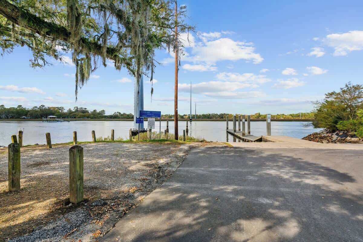 A lakeside park with a paved walkway, wooden posts, and a dock extending into the water.
