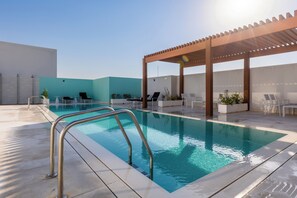 A rooftop pool with a pergola and lounge chairs. - Waves - Refined Studio with Balcony & City Views in Luma21 (Dubai)