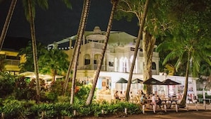 A white building with a dome and arched windows, surrounded by palm trees and outdoor seating areas. - Palm Cove Studio Apartments (Palm Cove)
