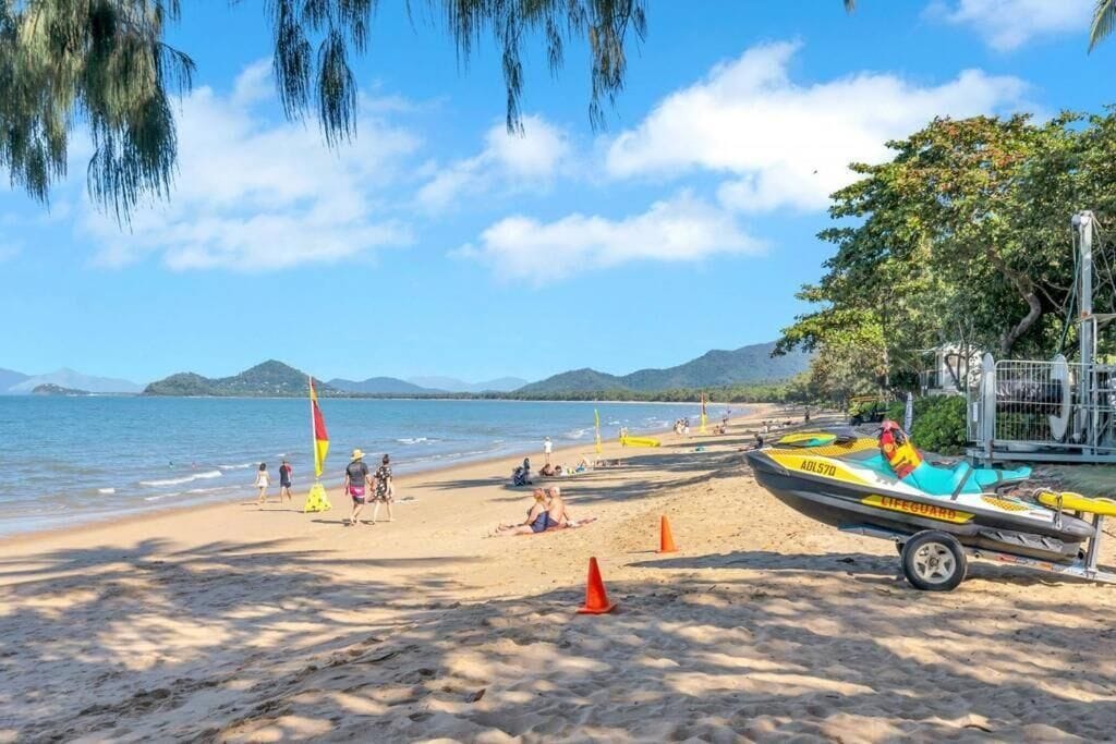 Une plage avec un poste de surveillance des sauveteurs, un jet ski et des gens qui se détendent sur le sable.