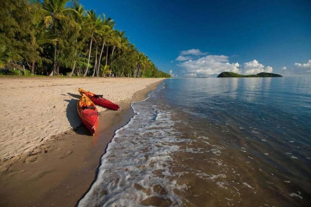 A beach with a red kayak and a small island in the distance.