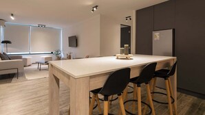 Una cocina moderna con una isla grande, armarios oscuros y un refrigerador empotrado.