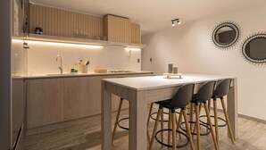 Una cocina moderna con una isla central, armarios de madera y un comedor con taburetes.