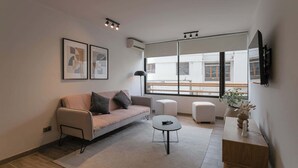 Una sala moderna con sofá, mesa de centro y un ventanal que ofrece vistas a un balcón.
