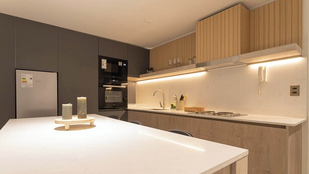 Una cocina moderna con una isla central, electrodomésticos integrados y armarios de madera.