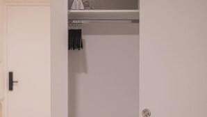 A white bathroom with a towel rack, a mirror, and a shelf.