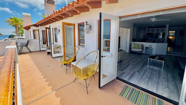 A modern house with a patio, two yellow chairs, and a view of the ocean. - Hamilton Cove Villa 9 58 With Zero Steps (Avalon)
