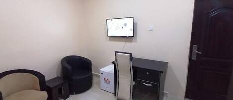 A small office space with a desk, chair, and a refrigerator.