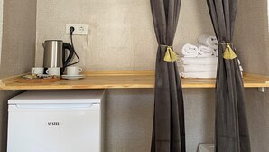 A kitchenette with a coffee maker, cups, and a small fridge. - Bak cafe& pansiyon (Ayvalik)